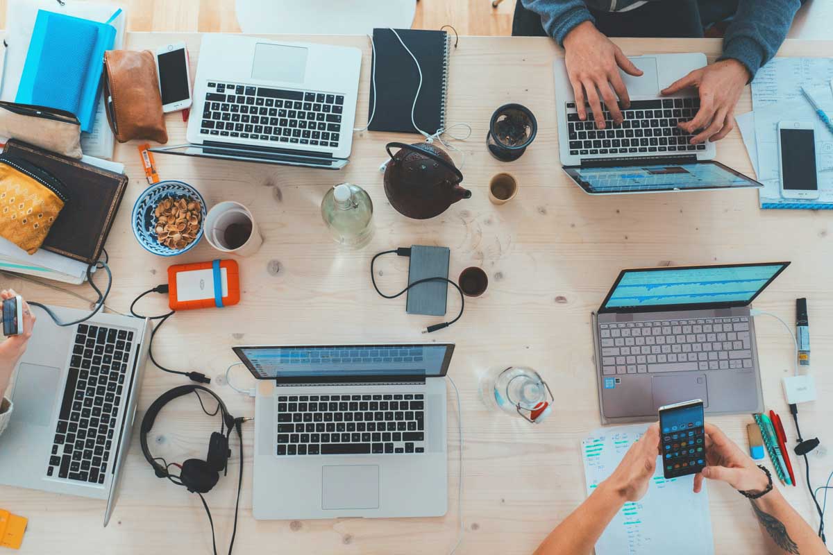 Aerial view of students laptops and cellphones on a desk while they study using AI tools